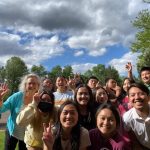 4-H Educator waves with a bunch of Hmong teens in a park setting.