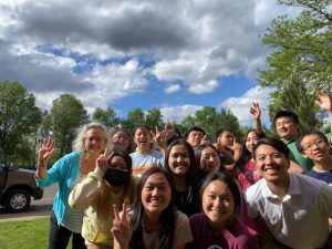 4-H Educator waves with a bunch of Hmong teens in a park setting. 