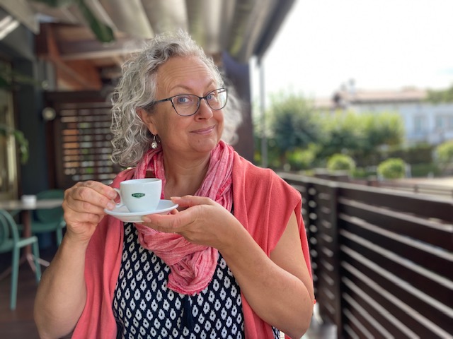 Family educator Luisa holding a cup of coffee, with a wry smile.