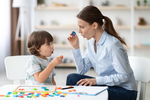 Female speech therapist curing child's problems and impediments. Little boy learning letter O 
